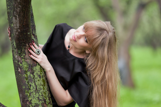The beautiful woman leaned the elbows on a tree - Photo, image