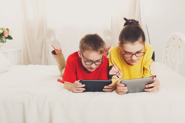 Két gyerekek játszanak ágyon tabletta - Fotó, kép
