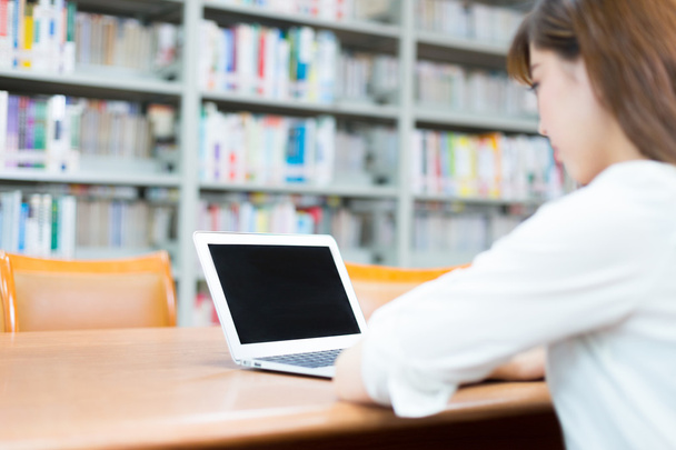 menina asiática com laptop na biblioteca da escola
 - Foto, Imagem