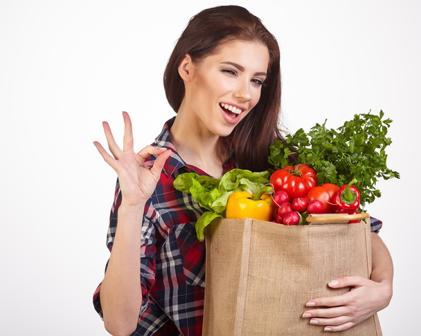 Isolated woman holding a shopping bag full of vegetables - 写真・画像