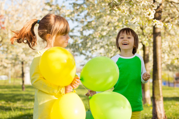Cute little girl and boy, friends, playing with balloons in a bl - Foto, Bild