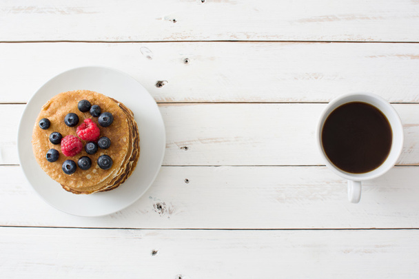Pancakes with blueberries and raspberries on white wood - Fotó, kép