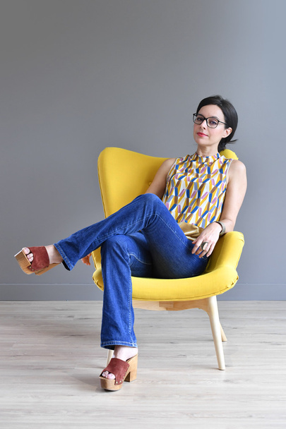  woman relaxing in yellow armchair - Foto, Imagem