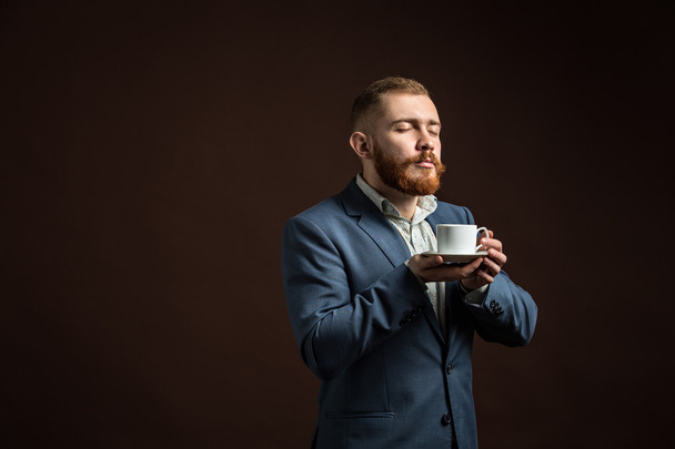 Handsome bearded man enjoying smell of coffee - Zdjęcie, obraz