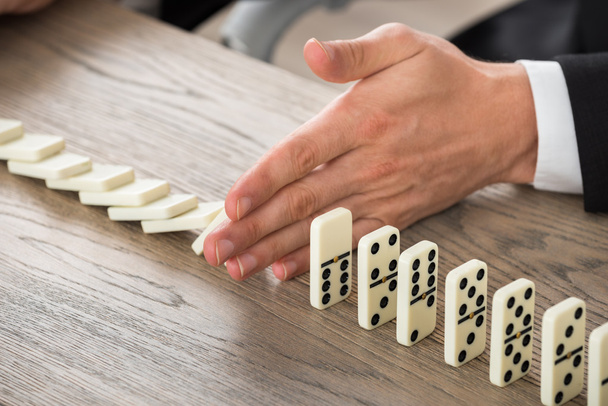 Businessman Stopping Dominoes From Falling - Foto, Bild