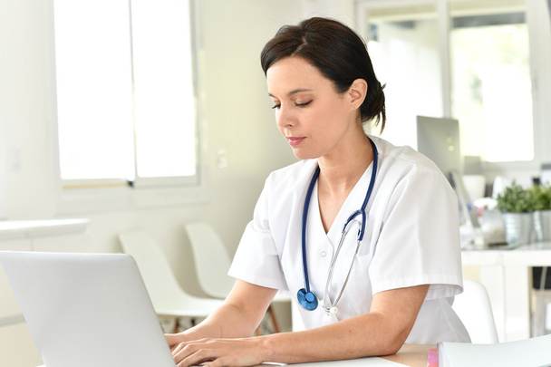 Doctor working on laptop computer - Foto, afbeelding