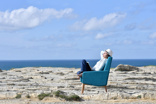 Woman in armchair relaxing on a cliff - Fotó, kép