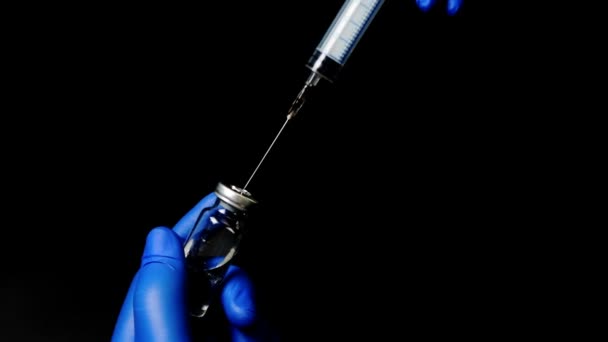 Lekarz w niebieskie rękawice zbieranie leku do strzykawki - Materiał filmowy, wideo