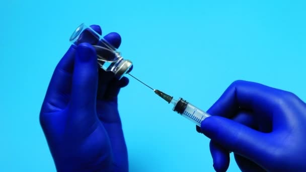 Médico con guantes azules recogiendo un medicamento en la jeringa
 - Metraje, vídeo