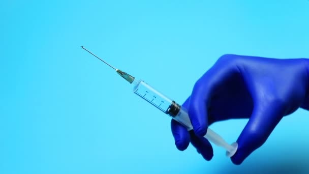 Médico con guantes azules recogiendo un medicamento en la jeringa
 - Imágenes, Vídeo
