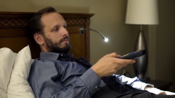 businessman watching TV lying on bed at night - Footage, Video