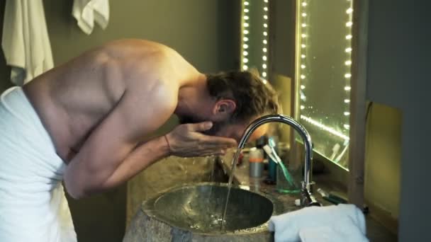 man in towel washing his face in bathroom - Кадри, відео
