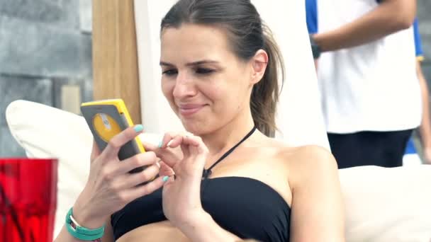pretty woman using smartphone on sunbed - Filmati, video