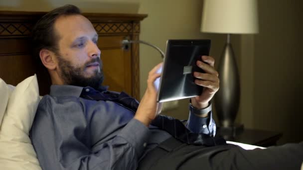 businessman with tablet computer on bed at night - Filmati, video