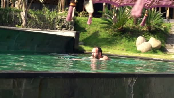 Young man swimming in pool - Felvétel, videó