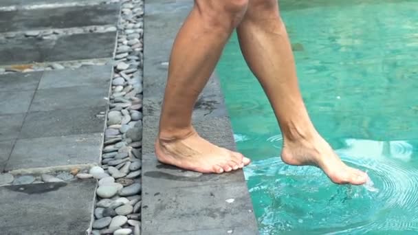 Male feet playing with water in swimming pool - Materiał filmowy, wideo