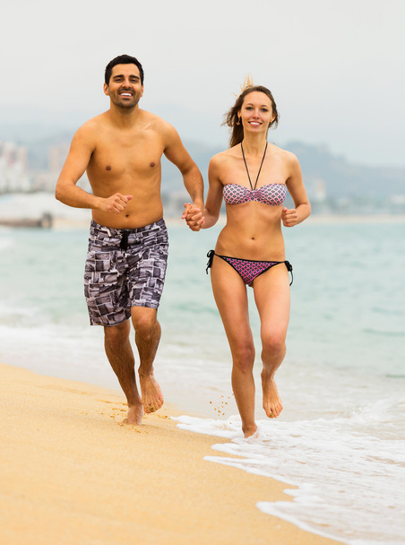 Pariskunta juoksemassa yhdessä meren rannalla
 - Valokuva, kuva