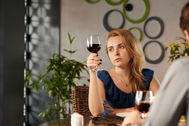 Zamyślony smutna kobieta przy lampce wina - Zdjęcie, obraz