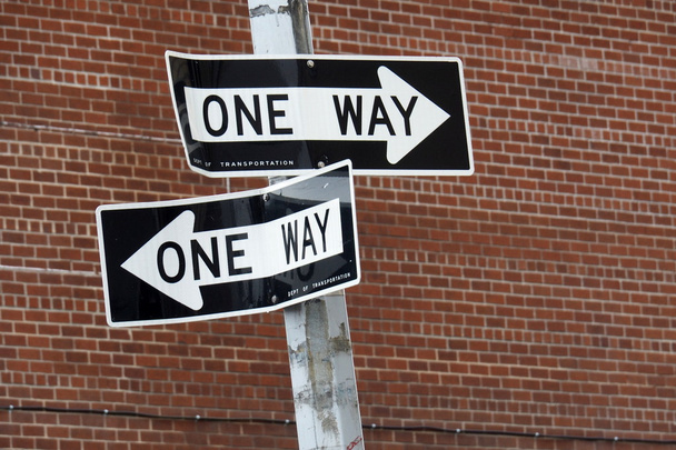 İki bir yol işaretleri kırmızı tuğla duvar önünde iki farklı yönlere işaret - Fotoğraf, Görsel