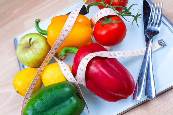 Paprikat, tomaatit, omena ja sitruunat mittakaavassa ruokailuvälineet ja t
 - Valokuva, kuva
