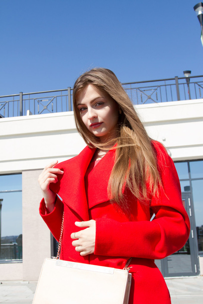 Zakenvrouw in een rode jas op de achtergrond van kantoorgebouw  - Foto, afbeelding