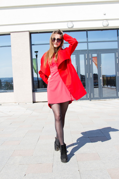 Mulher de negócios em um casaco vermelho no fundo do prédio de escritórios
  - Foto, Imagem