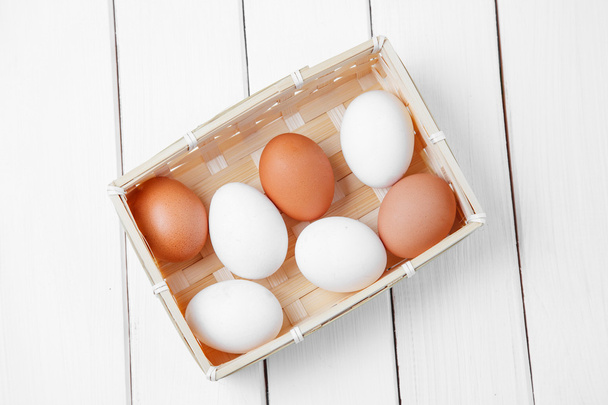 frische Eier in einem Korb auf einem hölzernen Hintergrund. Horizontalschuss - Foto, Bild