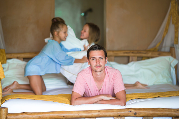 Father with two adorable little girls having fun in bed - Photo, Image