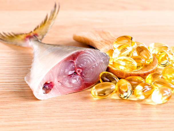 Omega 3 cápsulas de aceite de pescado en cuchara de madera con pescado fresco se
 - Foto, imagen