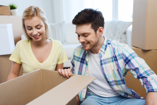 smiling couple with big boxes moving to new home - Foto, Imagen