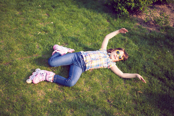 dziewczyna sobie Wrotki, siedząc na trawie w parku - Zdjęcie, obraz
