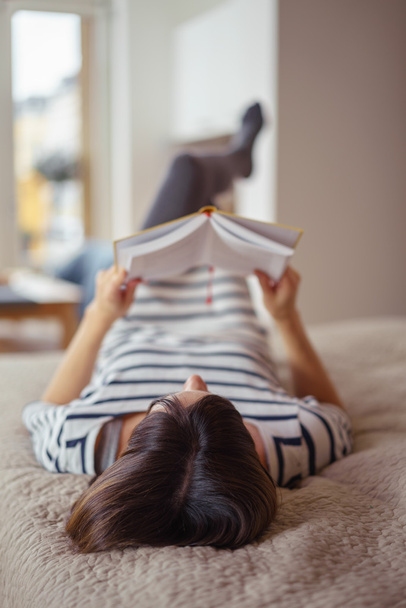 Jovem relaxante com um livro em casa
 - Foto, Imagem