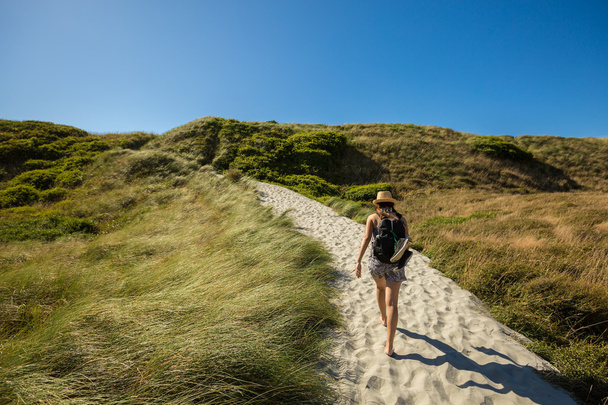 young adult woman walking on sand track at Wharariki Beach - Foto, imagen