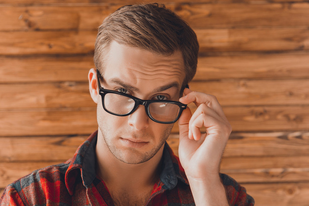 Attractive young serious man  touching his glasses - Foto, immagini