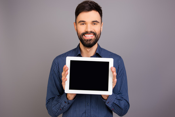 Cheerful handsome man demonstrating black screen of tablet - Fotó, kép
