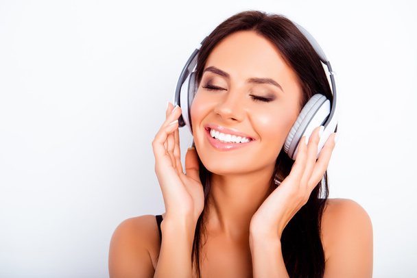 Pretty young woman listening music in headphones with closed eye - 写真・画像