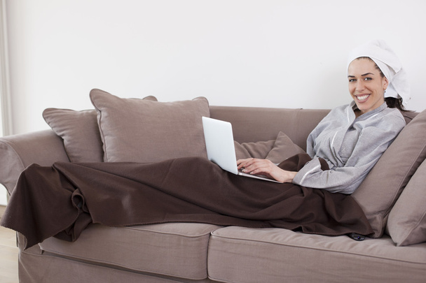Woman lying on the couch and working on laptop in the living room - Fotoğraf, Görsel