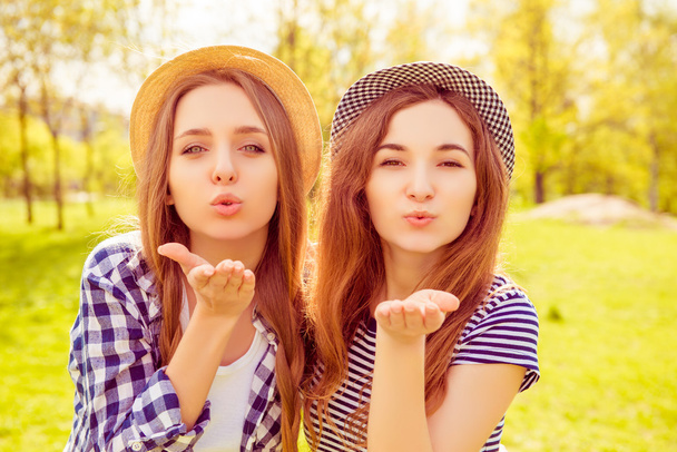 Portrait of beautiful girls in hats sending airy kiss - Photo, image