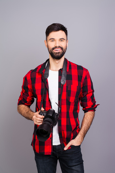 Handsome smiling photographer with camera on gray background - Foto, Bild