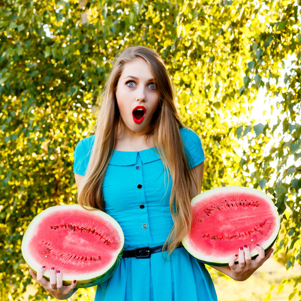 Beautiful blonde girl holding two halves of a sliced watermelon - Photo, Image