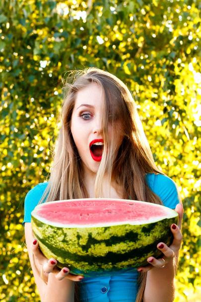 Beautiful blonde girl in a blue dress holding a sliced watermelo - Fotoğraf, Görsel