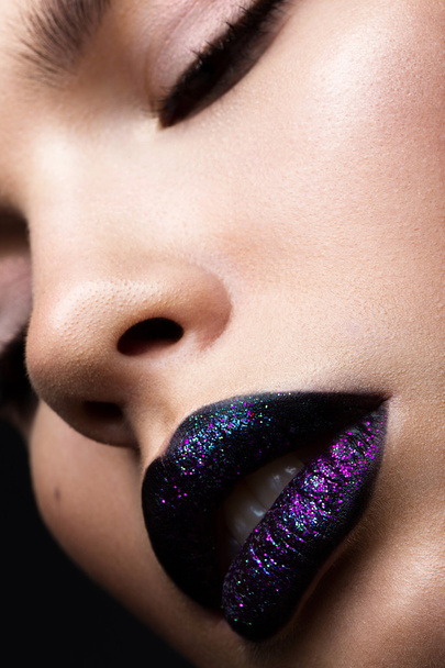 Portrait of a beautiful girl. Brilliant glossy lips closeup. Purple glitter on black lipstick - 写真・画像