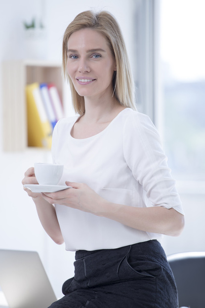 Деловая женщина в офисе пьет кофе
 - Фото, изображение