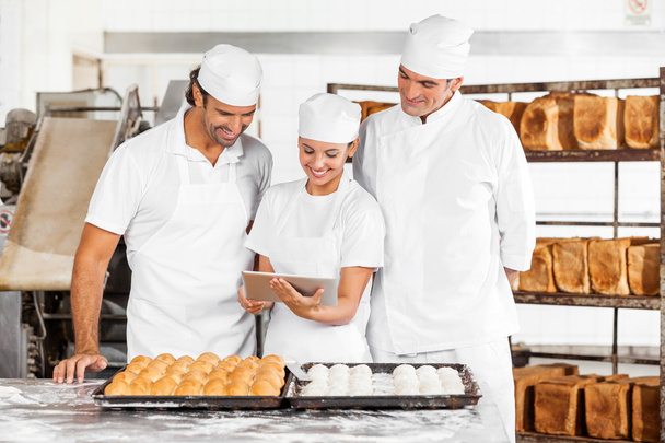Bakers Using Tablet Computer While Preparing Breads In Bakery - Foto, Imagem