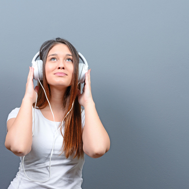 Portrait of girl enjoying her music against gray background - Фото, зображення
