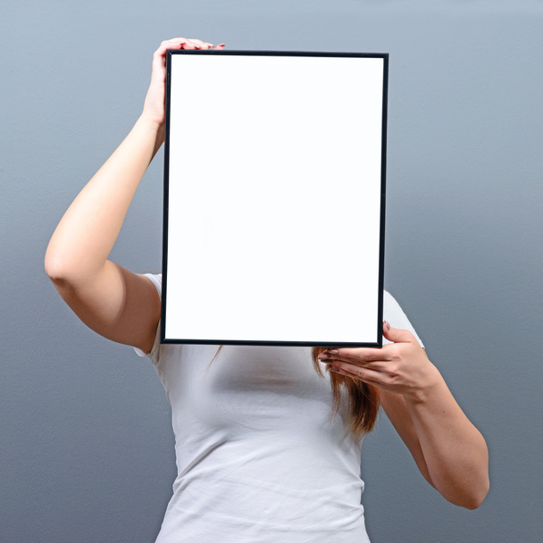 Portrait of woman hiding behind blank sign board - Valokuva, kuva