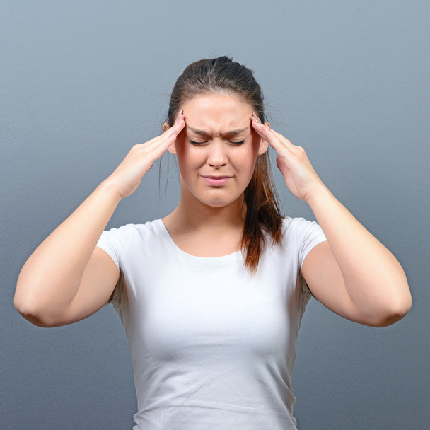 Portrait of woman with headache against gray background - Photo, Image