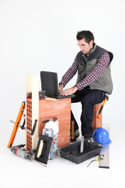Bricklayer with a laptop - Фото, изображение