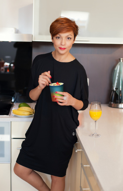 Smiling young woman eating fresh fruits - Valokuva, kuva