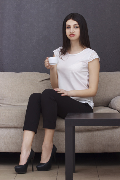 Woman drinking coffee on sofa - Foto, Bild